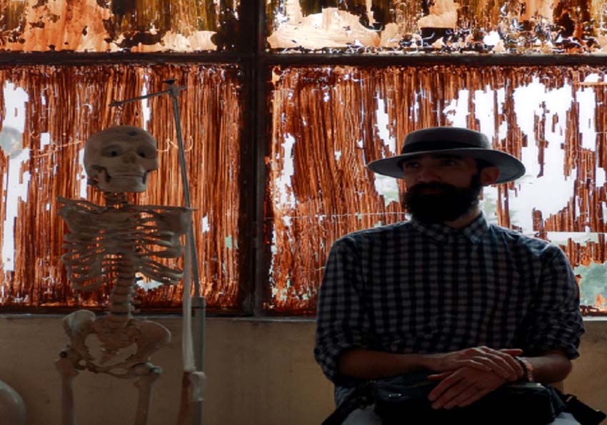 Still. A man sitting next to a skeleton